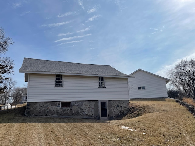 rear view of property with a yard and a shingled roof