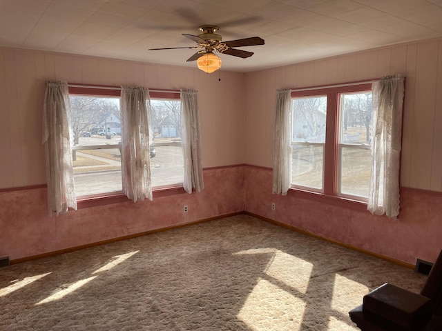 spare room featuring baseboards, visible vents, a ceiling fan, and carpet