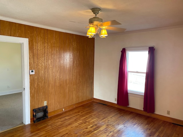 empty room featuring baseboards, wood-type flooring, ornamental molding, and a ceiling fan