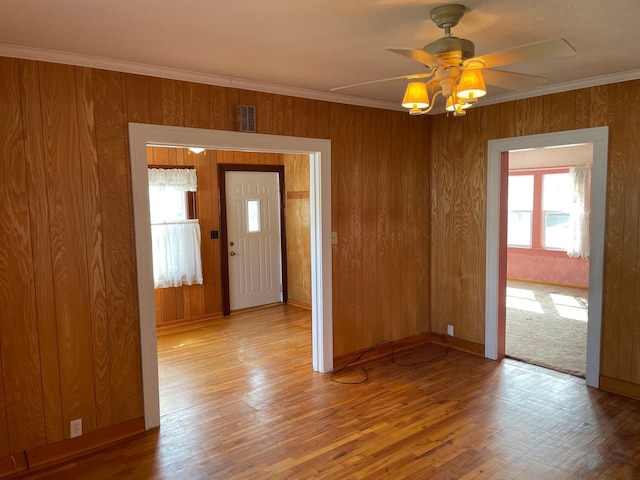 unfurnished room featuring wood finished floors, a ceiling fan, visible vents, and ornamental molding