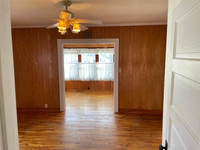 spare room featuring wood finished floors, a ceiling fan, visible vents, and ornamental molding