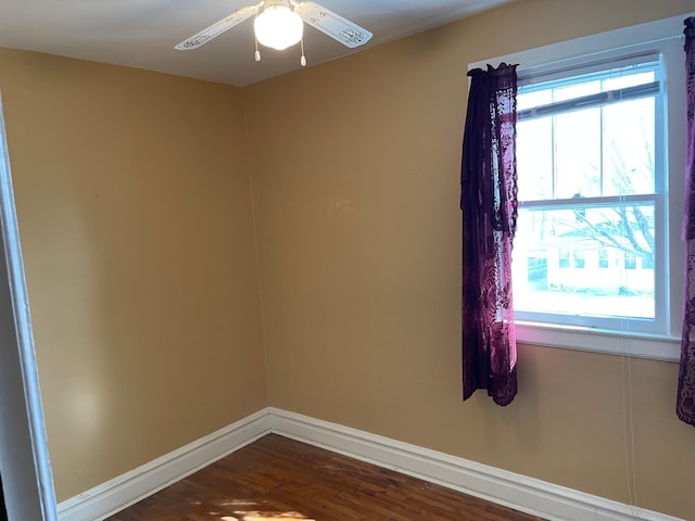 empty room with baseboards, dark wood-style floors, and a ceiling fan