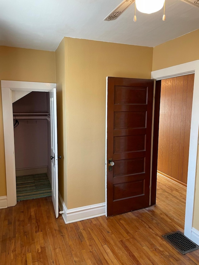 unfurnished bedroom with a closet, visible vents, light wood-type flooring, and baseboards