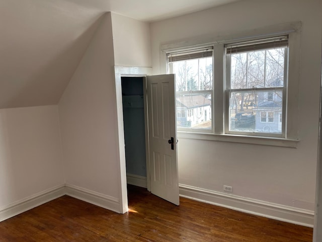 unfurnished bedroom featuring lofted ceiling, baseboards, and wood-type flooring