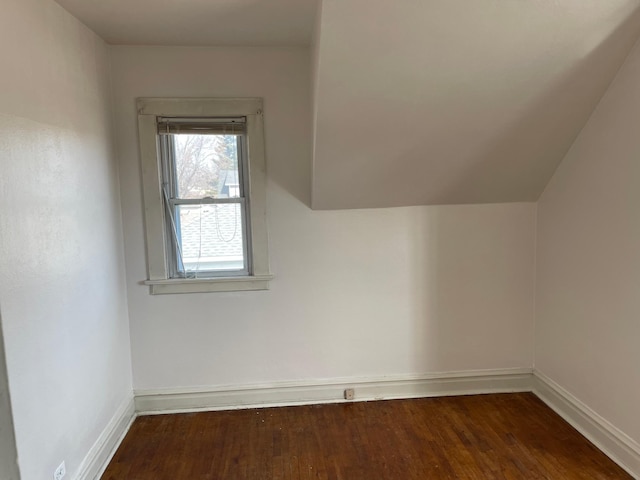 bonus room featuring dark wood finished floors, vaulted ceiling, and baseboards