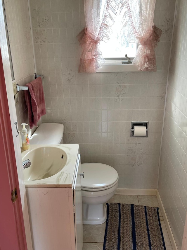 bathroom featuring toilet, tile walls, vanity, and tile patterned flooring