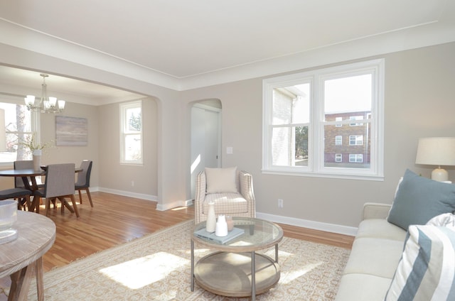 living area with arched walkways, light wood-type flooring, and baseboards