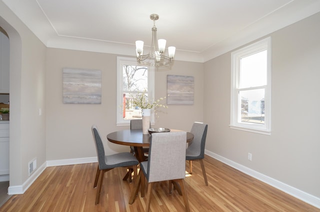 dining area with visible vents, arched walkways, light wood finished floors, and baseboards