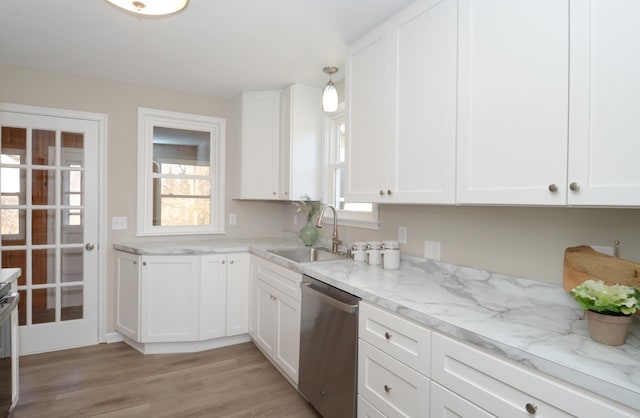 kitchen with light stone countertops, dishwasher, light wood-style flooring, white cabinetry, and a sink