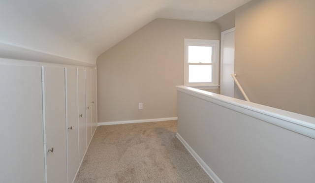 corridor featuring lofted ceiling, carpet flooring, an upstairs landing, and baseboards