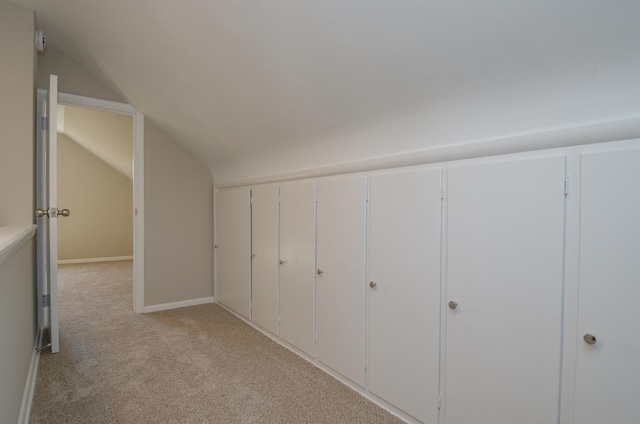 bonus room with baseboards, lofted ceiling, and light colored carpet