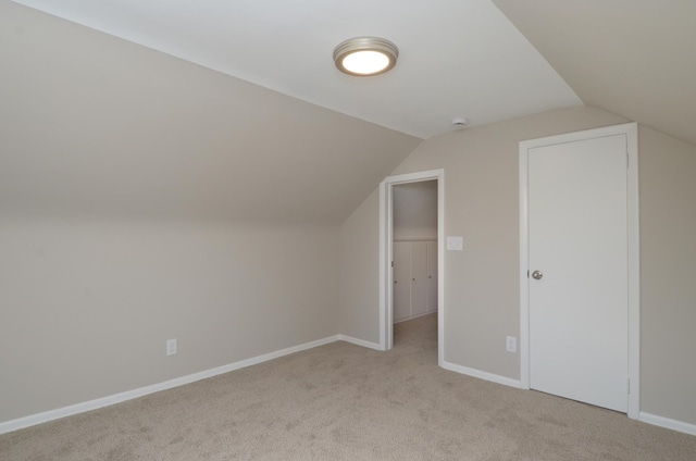 additional living space with lofted ceiling, light colored carpet, and baseboards