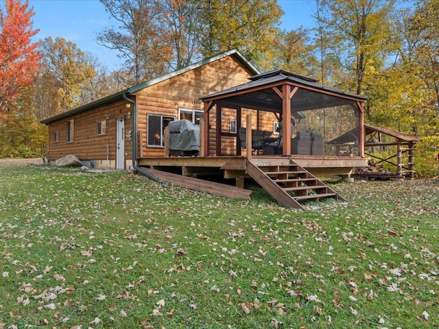 back of property featuring a yard, a wooden deck, faux log siding, and a sunroom