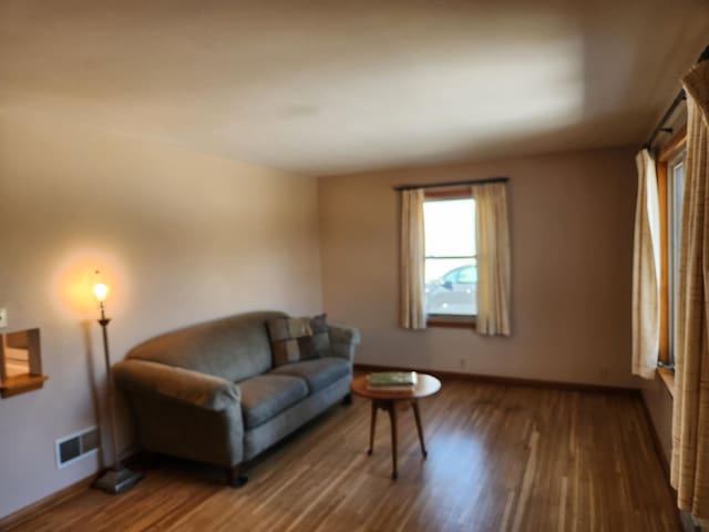 living area with visible vents, baseboards, and wood finished floors