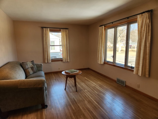 living area featuring plenty of natural light, wood finished floors, visible vents, and baseboards