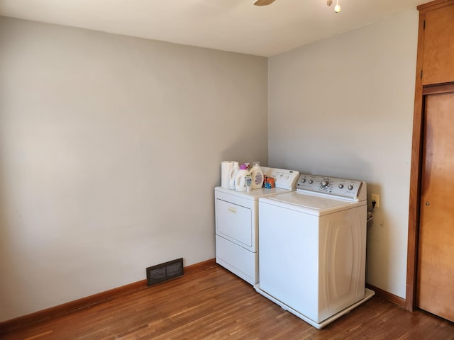 laundry room with visible vents, washer and dryer, wood finished floors, cabinet space, and baseboards