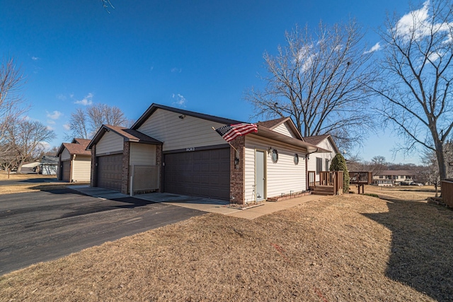 view of property exterior with a deck, a detached garage, and brick siding