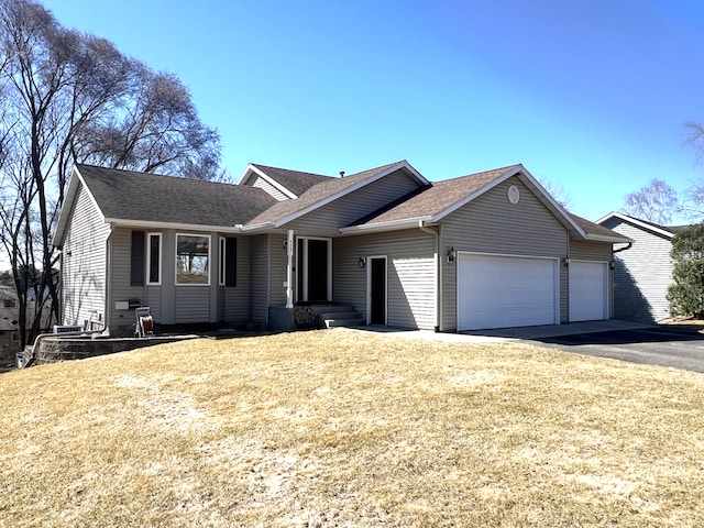 single story home featuring a garage, roof with shingles, a front yard, and aphalt driveway