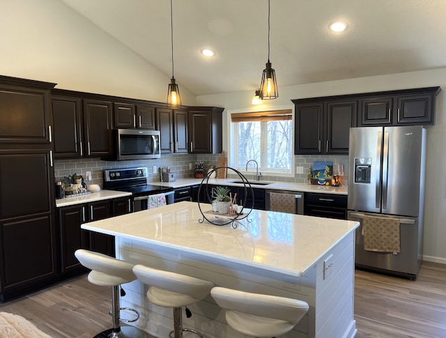 kitchen featuring a sink, appliances with stainless steel finishes, light wood-style flooring, and vaulted ceiling