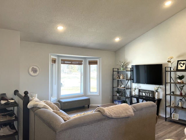 living area featuring baseboards, lofted ceiling, recessed lighting, wood finished floors, and a textured ceiling