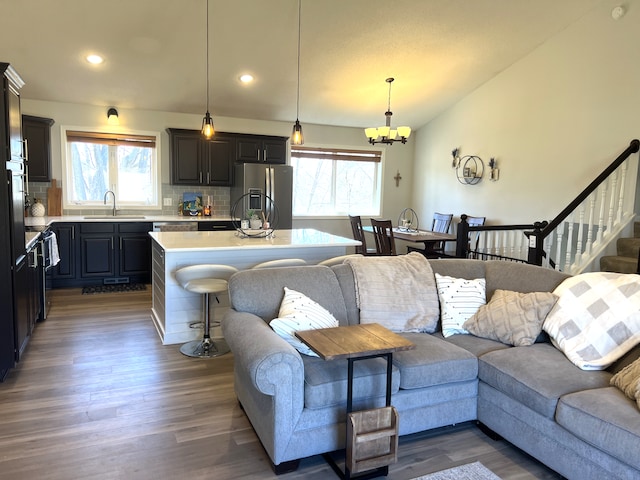 living area with lofted ceiling, an inviting chandelier, wood finished floors, and a healthy amount of sunlight