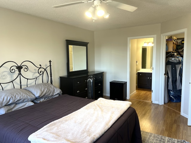 bedroom featuring baseboards, dark wood finished floors, a spacious closet, a closet, and a textured ceiling