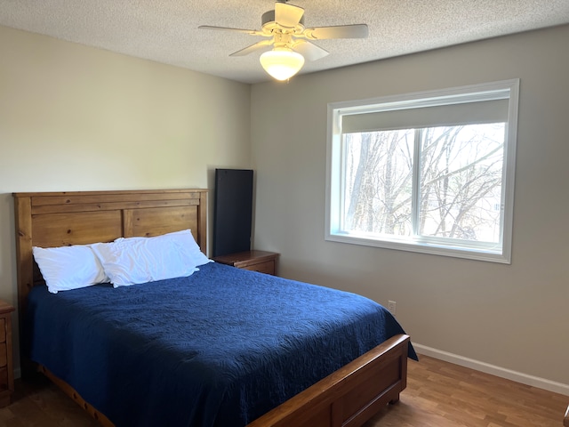 bedroom featuring a textured ceiling, a ceiling fan, baseboards, and wood finished floors