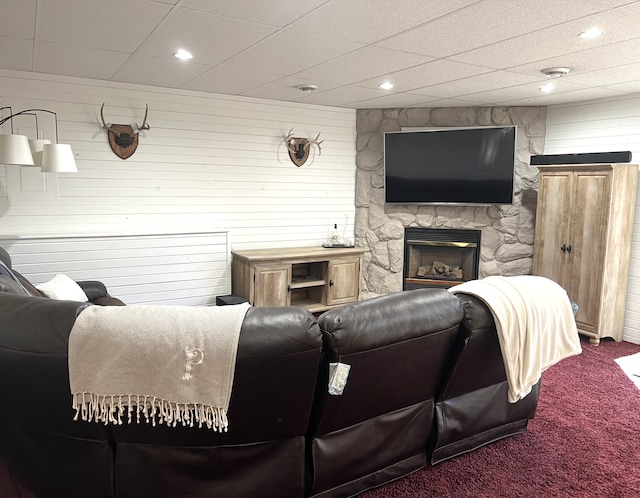 carpeted living room featuring recessed lighting, wooden walls, and a fireplace