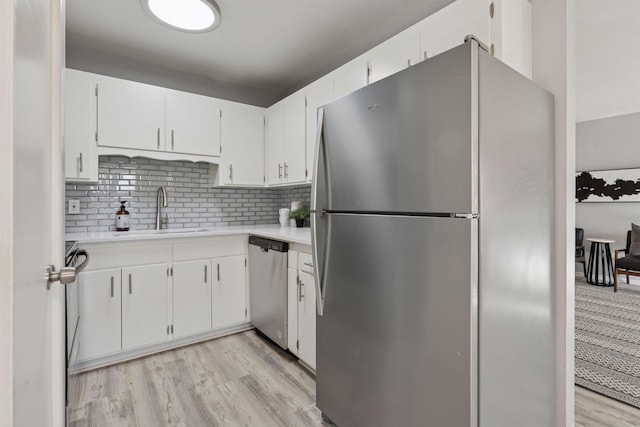 kitchen with light wood finished floors, light countertops, decorative backsplash, appliances with stainless steel finishes, and a sink