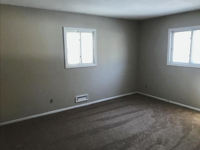 spare room with a textured ceiling, baseboards, and carpet