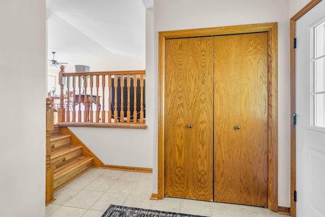 hallway featuring baseboards, tile patterned floors, lofted ceiling, and stairway