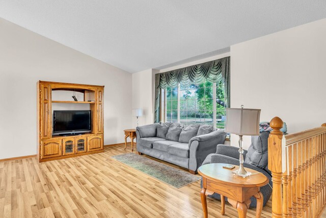 living room featuring light wood-style floors, vaulted ceiling, and baseboards