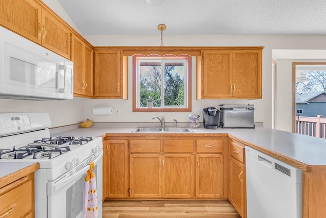 kitchen featuring white appliances, a sink, a peninsula, and light countertops