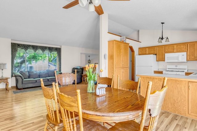 dining room with light wood-style floors, ceiling fan, a chandelier, and high vaulted ceiling