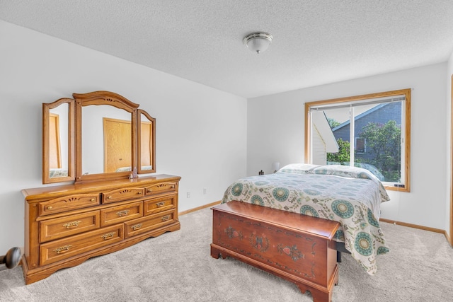 bedroom featuring light colored carpet, baseboards, and a textured ceiling
