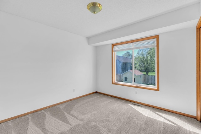 spare room featuring carpet and baseboards