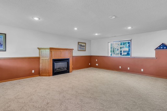 unfurnished living room with a fireplace, carpet, a textured ceiling, recessed lighting, and baseboards