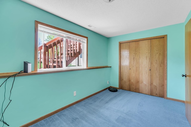 carpeted bedroom with baseboards, a textured ceiling, and a closet