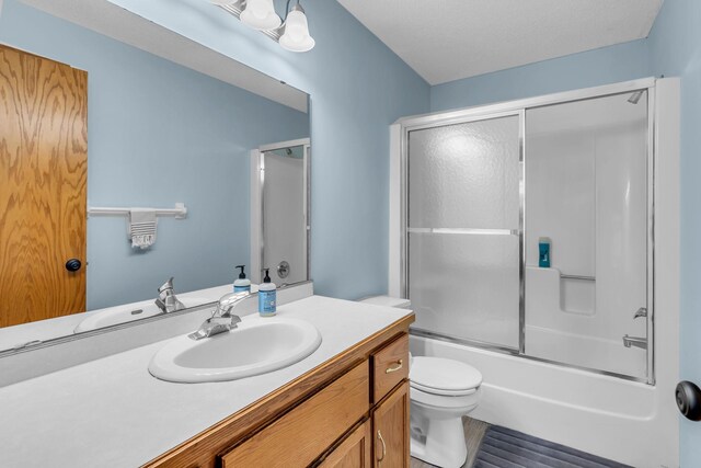 bathroom featuring toilet, vanity, and shower / bath combination with glass door