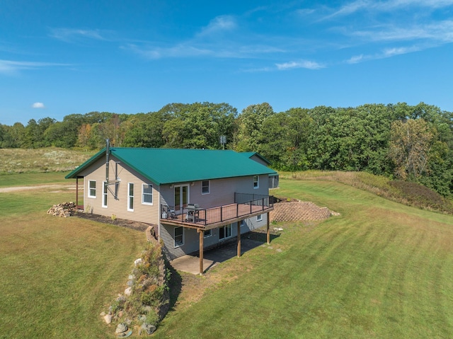 rear view of house with a wooden deck, a lawn, metal roof, and driveway