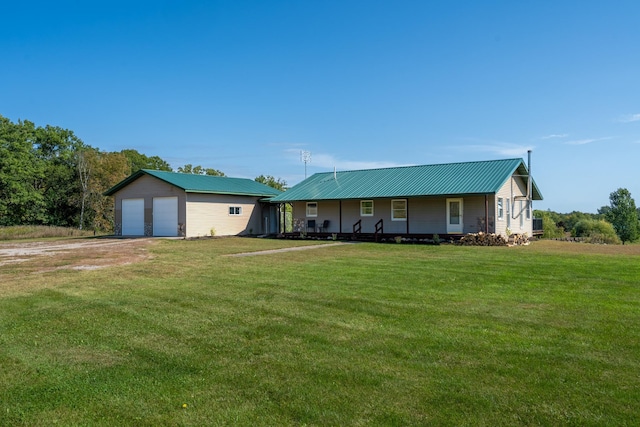 view of front of home with an outbuilding, a garage, metal roof, and a front lawn