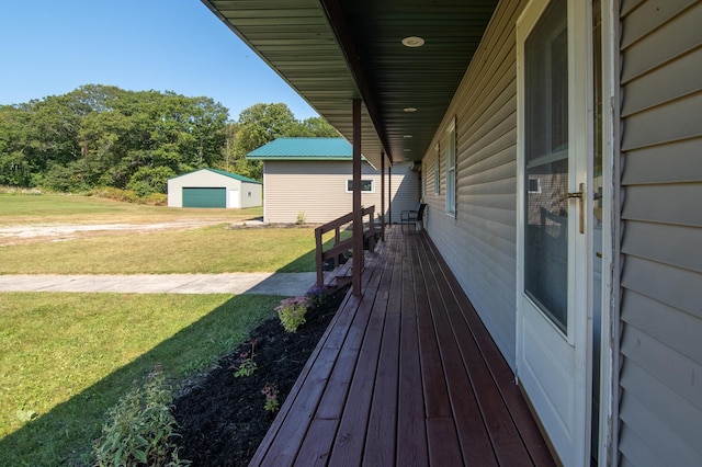 wooden deck featuring a detached garage and a yard