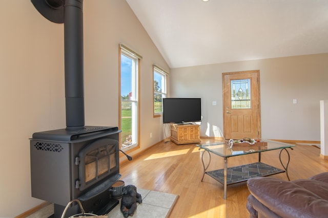 living area featuring light wood finished floors, baseboards, a wood stove, and lofted ceiling