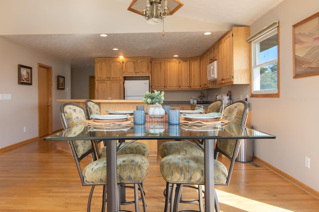 dining space with recessed lighting, baseboards, light wood finished floors, and a textured ceiling