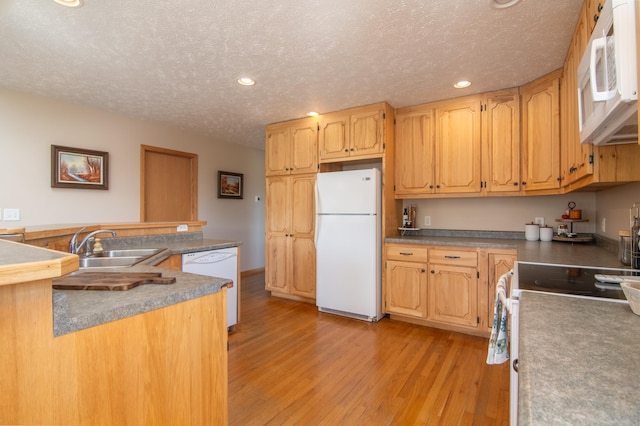 kitchen with white appliances, recessed lighting, a sink, a textured ceiling, and light wood-type flooring