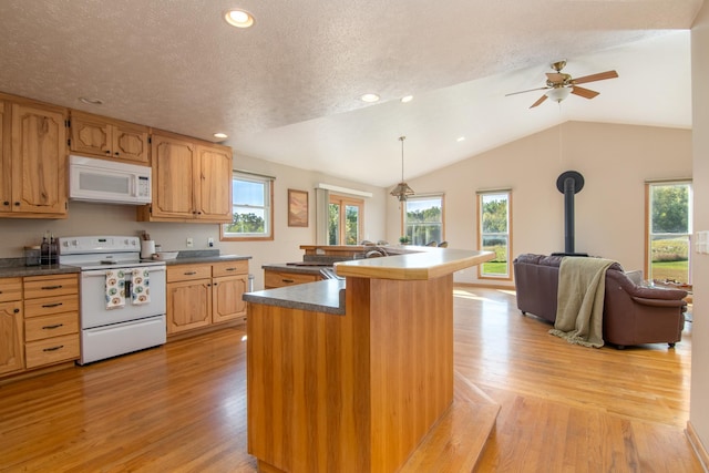 kitchen featuring light wood-type flooring, lofted ceiling, a wood stove, plenty of natural light, and white appliances