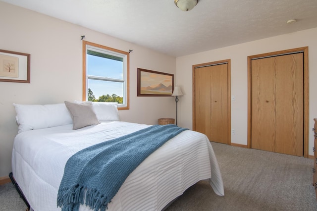 bedroom featuring baseboards, multiple closets, and carpet floors