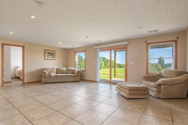 unfurnished living room featuring light tile patterned floors, visible vents, a textured ceiling, and baseboards