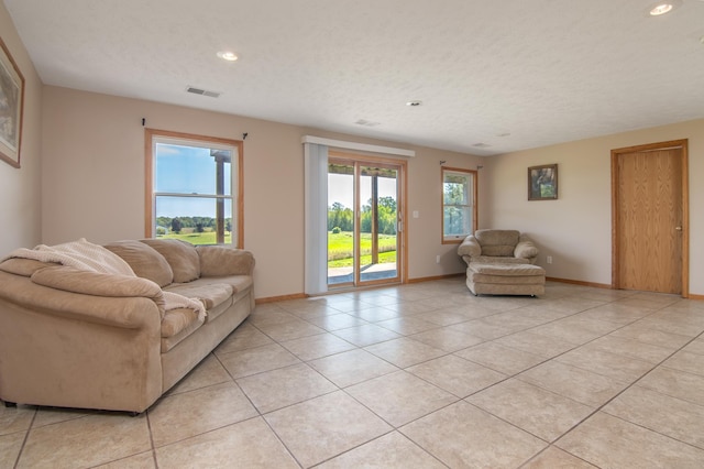 living area with visible vents, a textured ceiling, recessed lighting, light tile patterned floors, and baseboards