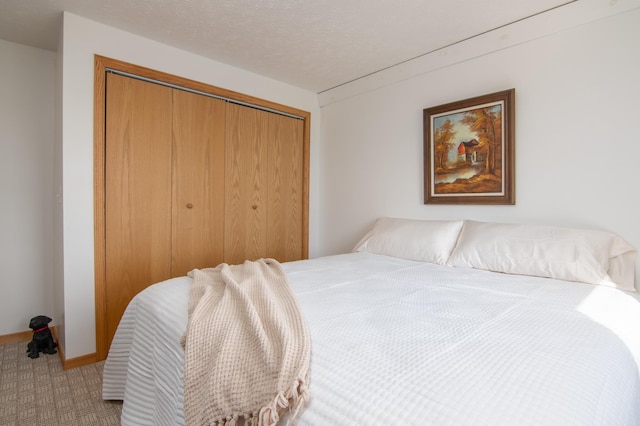 bedroom with a closet, carpet floors, a textured ceiling, and baseboards